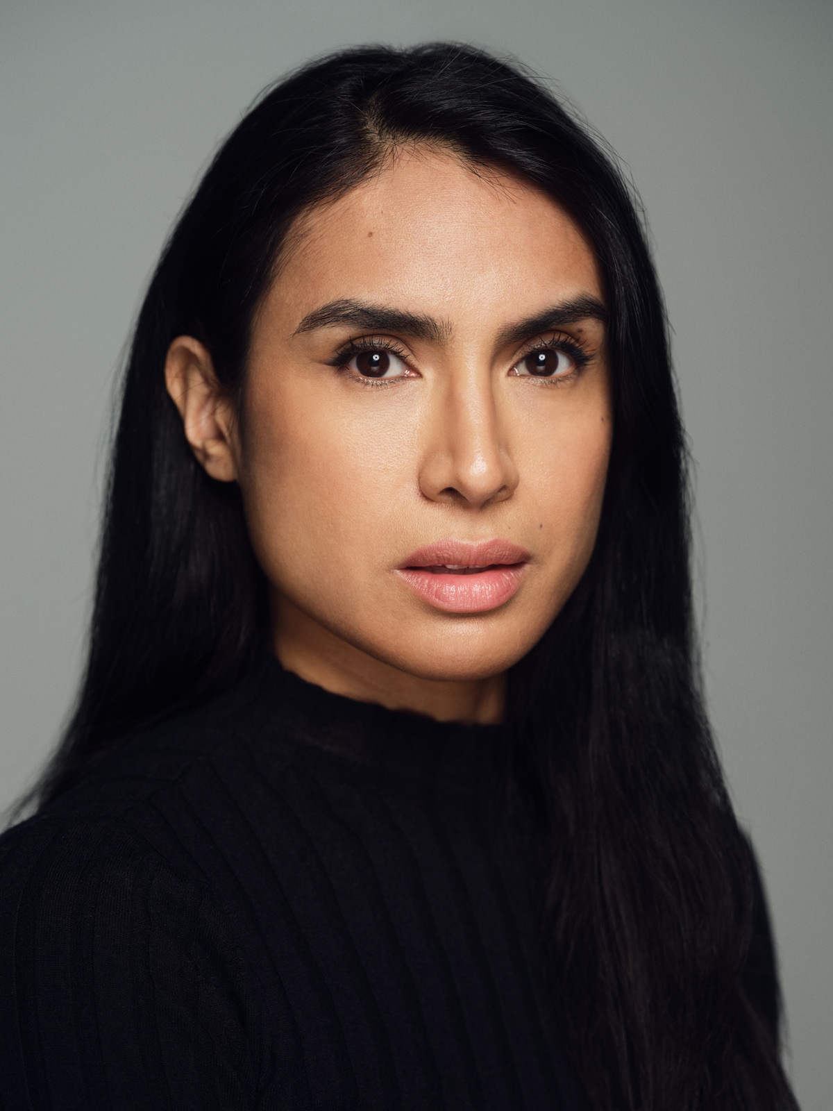 Close-up portrait of Yasmine Seifi in a black knit top, looking directly at the camera.